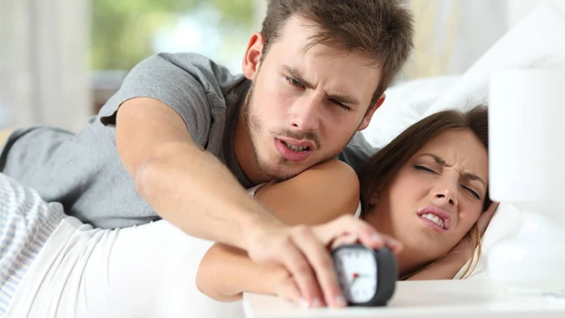 una imagen de una pareja dormitando la alarma