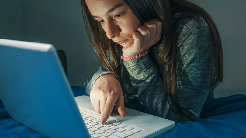 una imagen de una chica trabajando en un ordenador por la noche