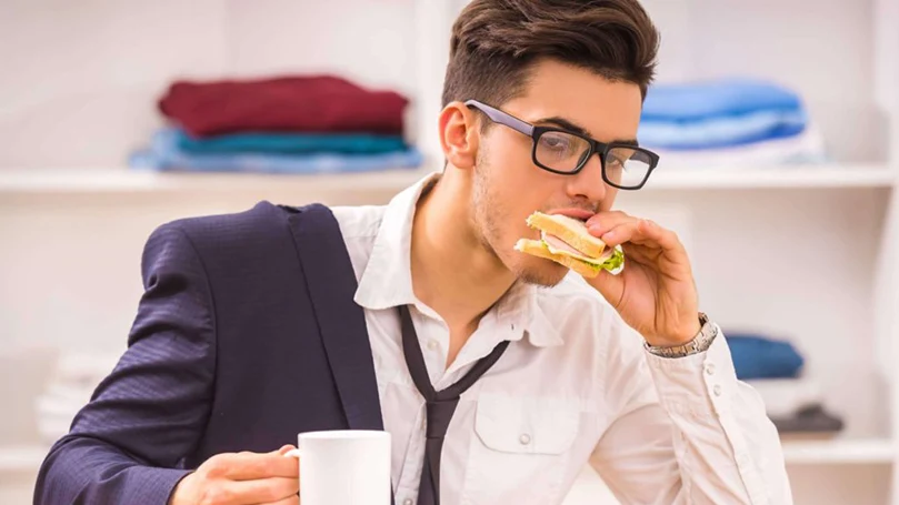 la imagen de un hombre que come rápido para llegar a tiempo al trabajo