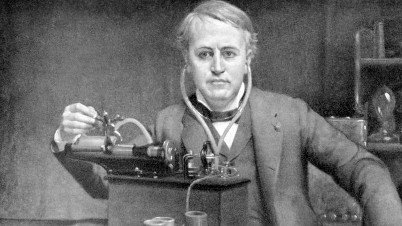 Una foto en blanco y negro de thomas edison delante de una máquina