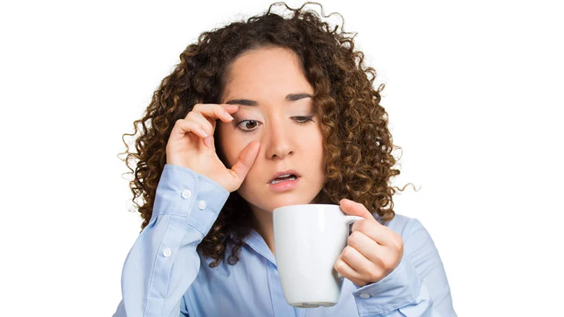 una imagen de una mujer que se despierta aturdida y bebe una taza de café