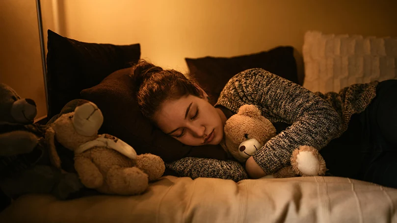 una mujer duerme en la cama con la luz encendida