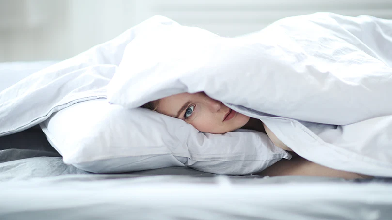 una imagen de una mujer tumbada en una cama cubierta con un edredón