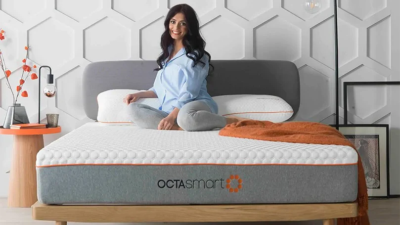 una imagen de una mujer sentada en el colchón Dormeo Octasmart Hybrid