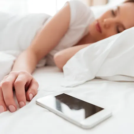 Una imagen de una mujer durmiendo junto a su teléfono