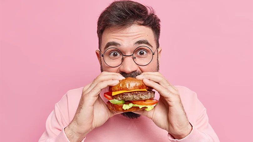 Imagen de un hombre comiendo una hamburguesa.