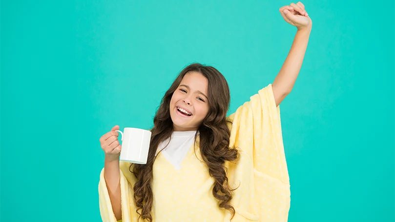 Imagen destacada de Una niña soñolienta con un vaso de leche antes de acostarse.