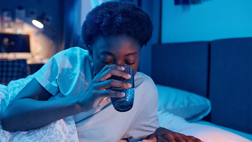 Imagen de una mujer bebiendo un vaso de agua antes de acostarse.