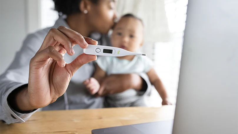 An image of a mother with her baby showing a thermometer