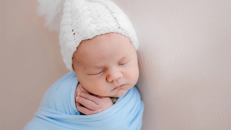 Imagen de un bebé con gorro mientras duerme.