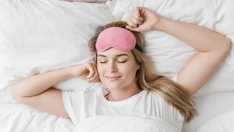 Una imagen de una mujer feliz en la cama gracias a haber dormido lo suficiente.