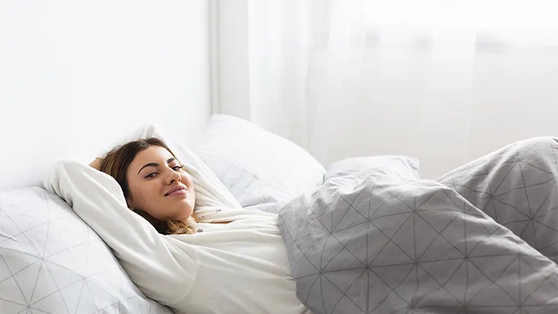 Una mujer relajada en la cama.