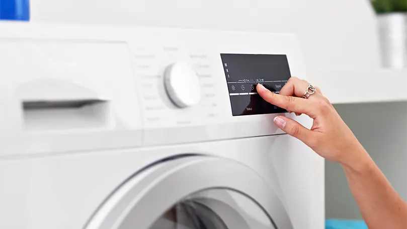 Imagen de una mujer preparando el secado a baja temperatura de la lavadora.