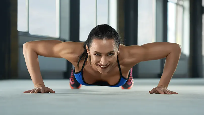 Una imagen de una mujer joven haciendo flexiones.