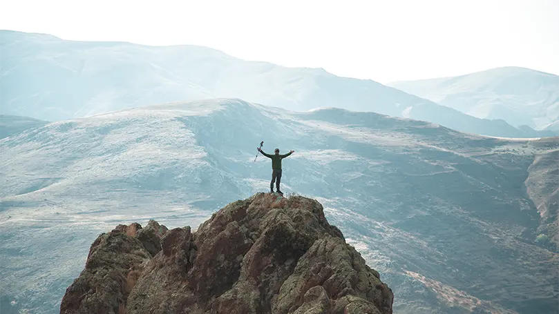 Un excursionista en la cima de una montaña.