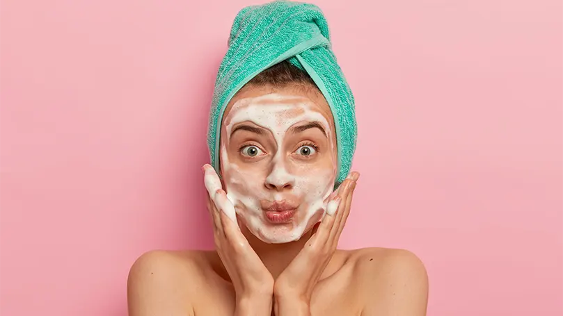 Imagen de una mujer poniéndose en la cara un limpiador facial.