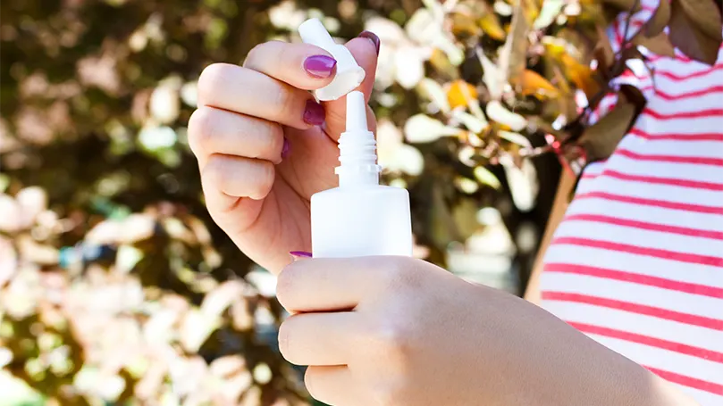 A female holding a nasal spray.