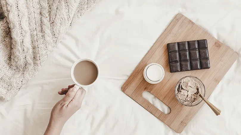 Una mano sosteniendo una taza de chocolate caliente.