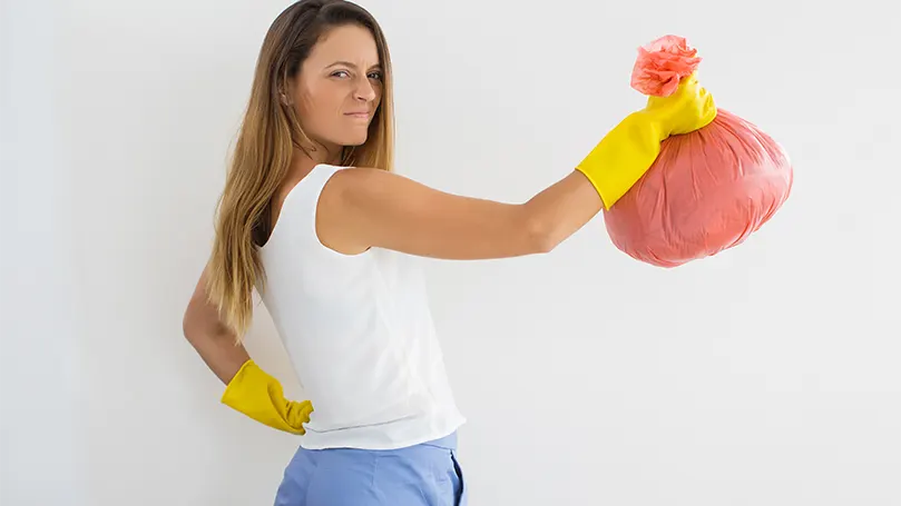 An image of a woman holding a trash bag.