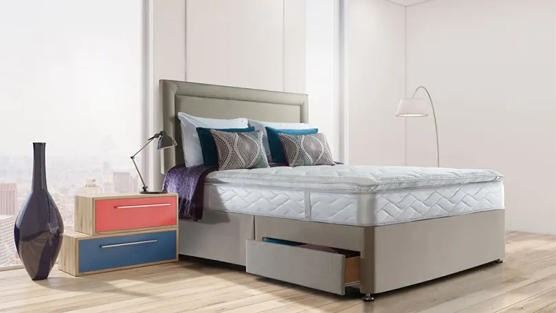 Una imagen del colchón Sealy Posturepedic Pearl Luxury Pillow Top en un dormitorio.