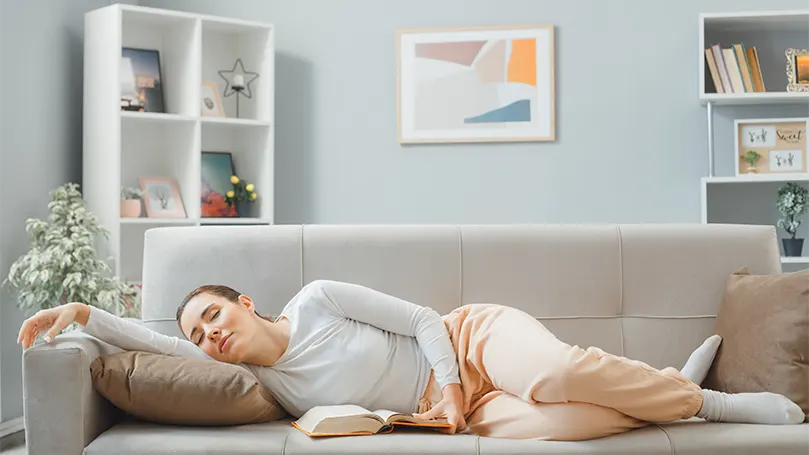 Imagen de una mujer durmiendo de lado en un sofá.