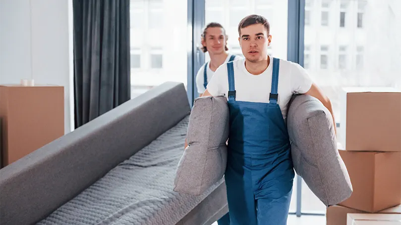 Una imagen de dos chicos de una empresa profesional transportando una cama.