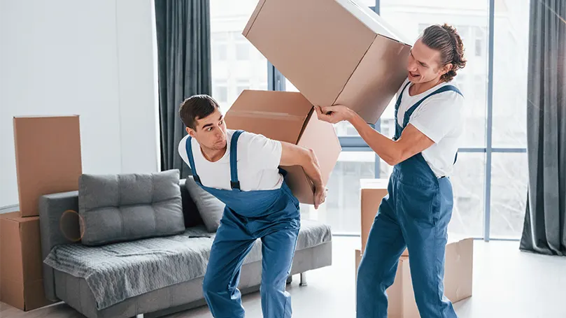 Imagen de dos jóvenes que transportan cajas.