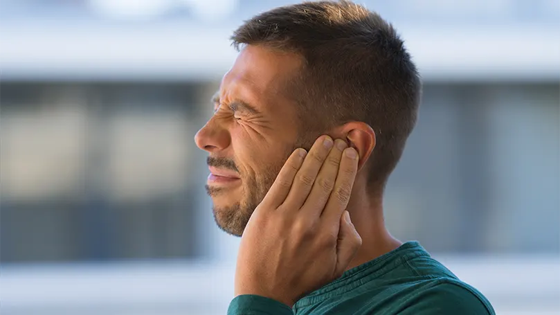 Un hombre con el tímpano roto se agarra la oreja por el dolor