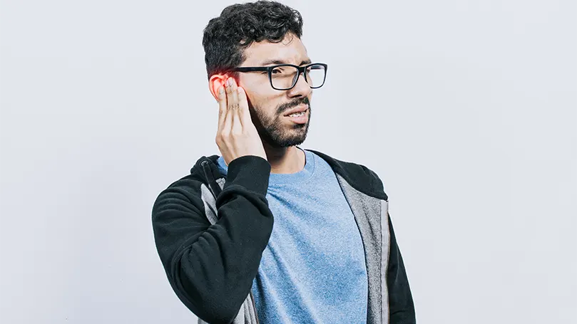 Un joven con gafas que sufre una rotura de tímpano.