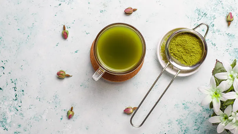 Una imagen de polvo de matcha junto a una taza de té matcha