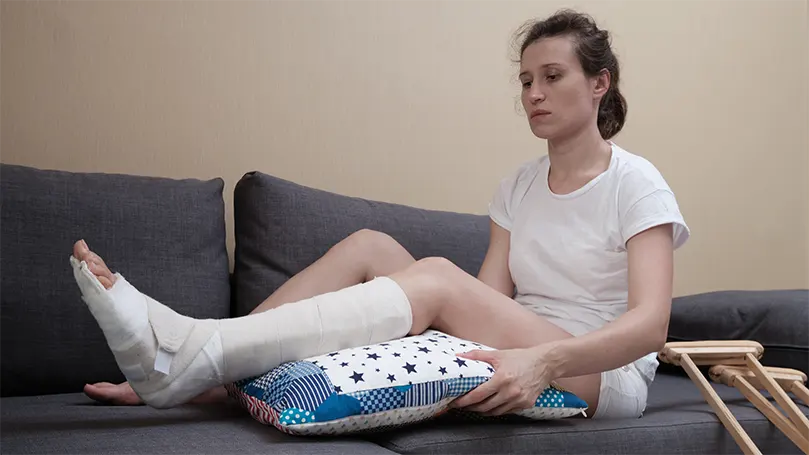 Imagen de una mujer en el sofá con una almohada bajo la rodilla.