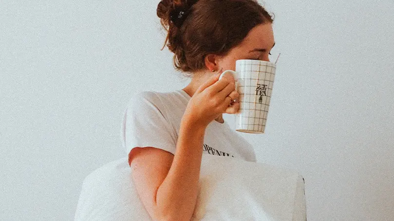 Una imagen de una mujer que se despierta del sueño y bebe té como parte de su rutina matutina.