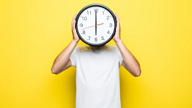 Un hombre con un reloj delante de la cabeza.