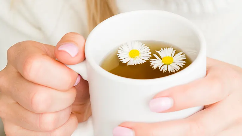 Una imagen de una persona con una taza de té en la mano para conciliar el sueño más fácilmente.