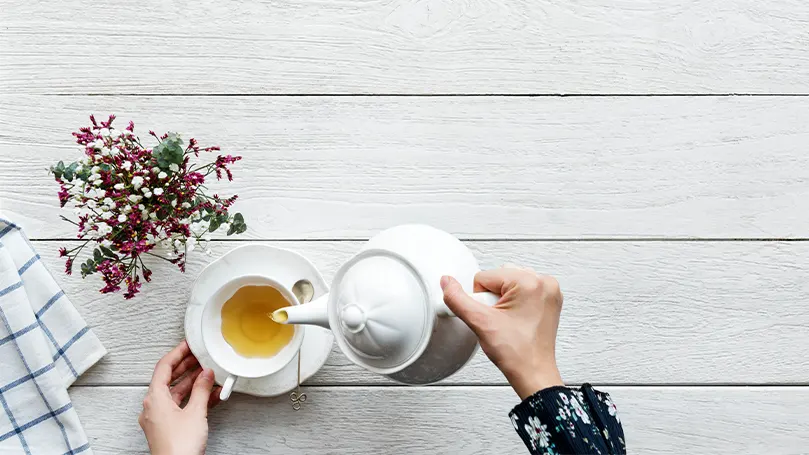 Una imagen de una persona vertiendo té blanco en su taza