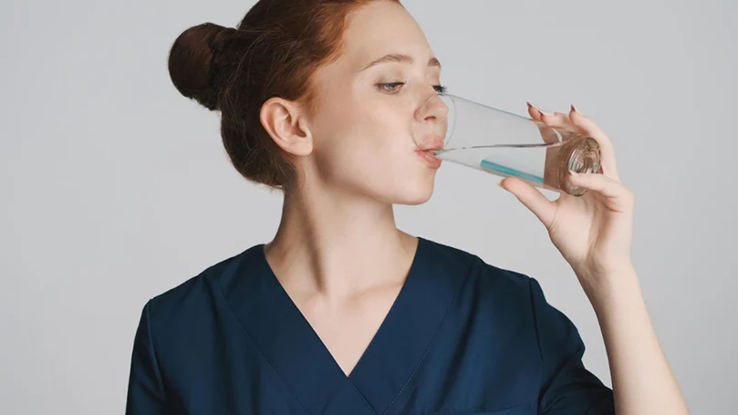 Una mujer bebiendo agua: uno de los mejores remedios caseros para la resaca.