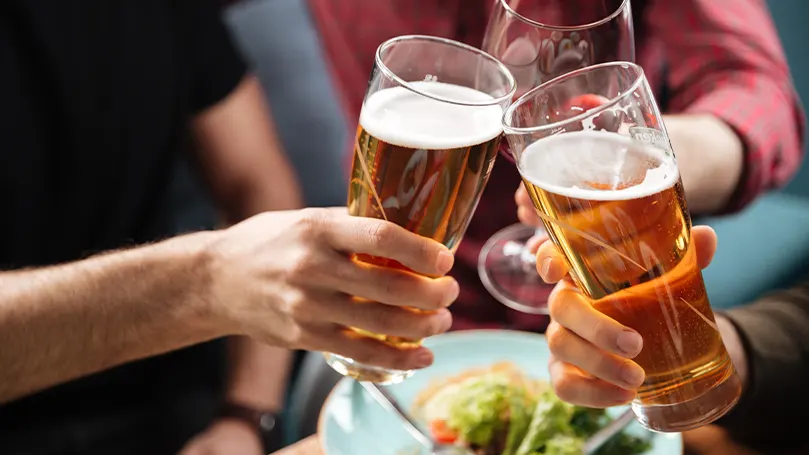 Una imagen de dos personas chocando sus cervezas