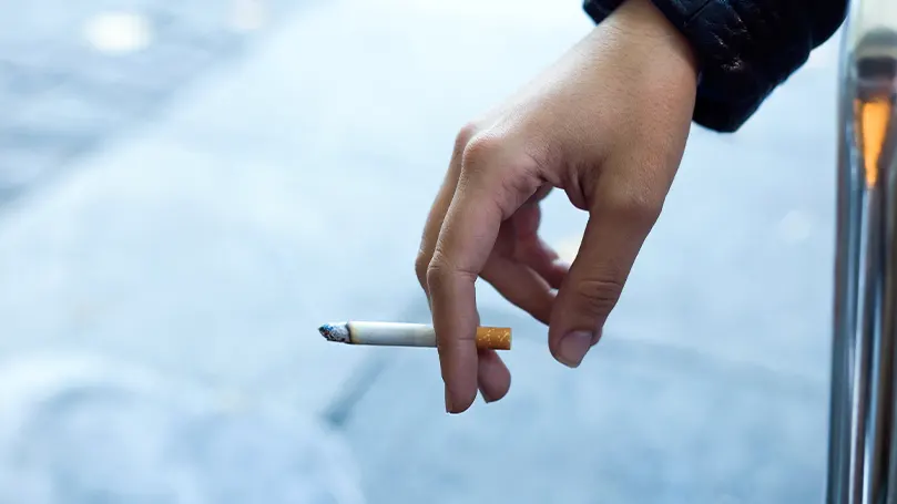 Imagen de la mano de una persona sosteniendo un cigarrillo.