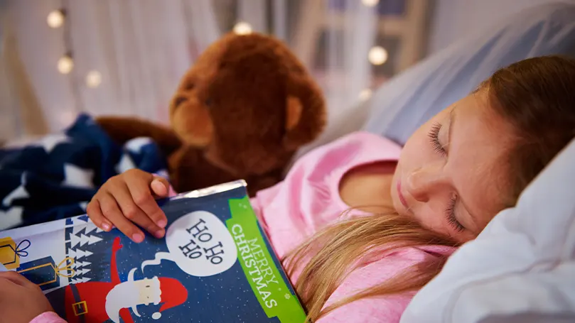 Imagen de un niño durmiendo y sosteniendo un libro.