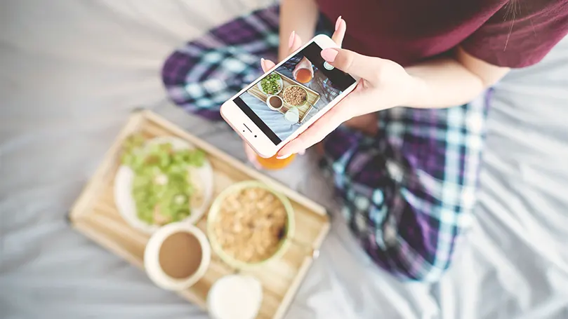 Una imagen de una persona comiendo en la cama y haciéndole una foto.