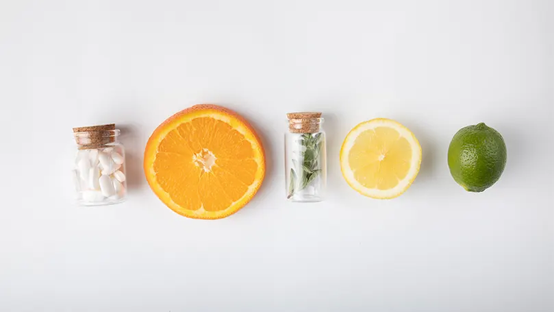 Una imagen de rodajas de naranja y hierbas en botellas.