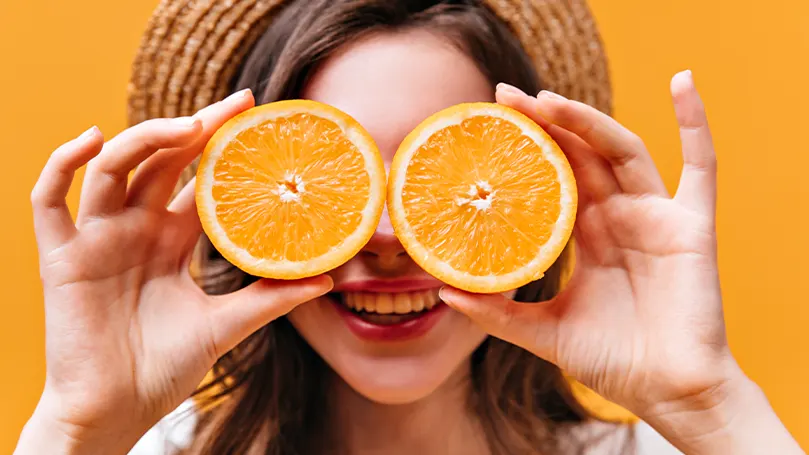 Imagen de una mujer con naranjas en la mano.