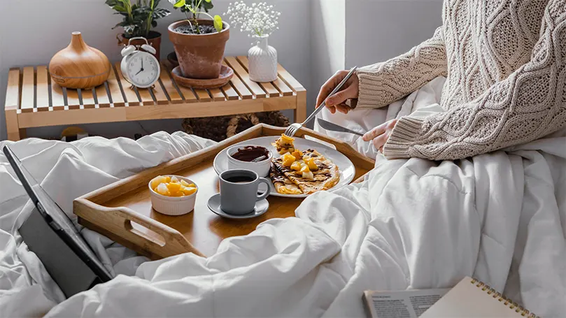 Imagen de una persona comiendo en la cama.