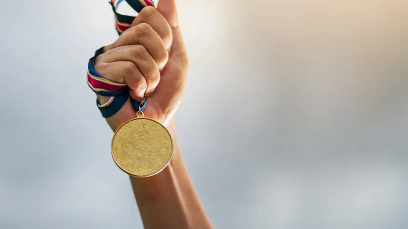 La imagen de una mano sosteniendo una medalla de oro