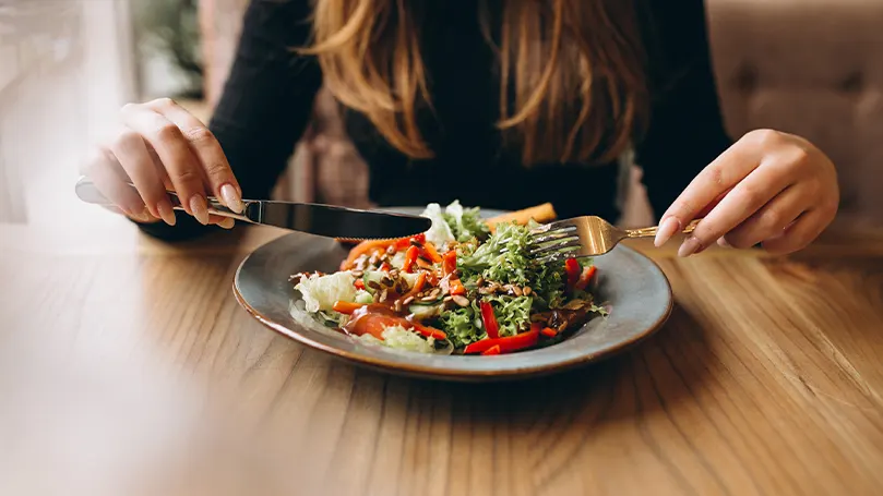 una mujer sentada en el able y comiendo una comida sana