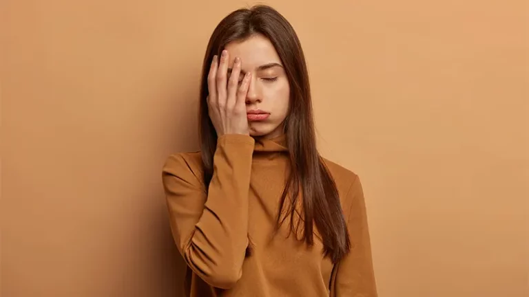 An image of a young woman holding a hand over her eye