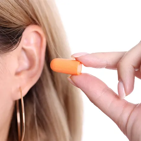 An image of a woman putting an earplug in