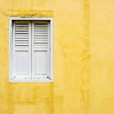 An image of a white window on a yellow wall.