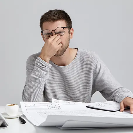 Un hombre cansado con gafas sentado a la mesa