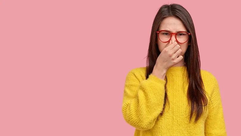 Una imagen de una mujer tapándose la nariz para evitar un olor desagradable